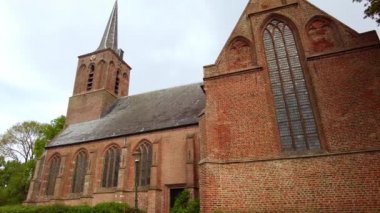 Hollanda 'nın Schellinkhout kentindeki küçük bir köyde güzel Gotik vitray pencereli kilise çan kulesi manzaralı 14. yüzyıl manzarası boyunca alçak bir açı.