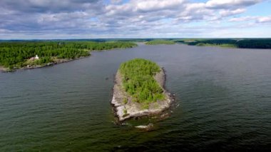 Varmland İsveç 'teki Vanern Gölü' nde birkaç turist ve çam ağacı olan kayalık bir adanın kuş bakışı görüntüsü. Sahilde geleneksel Falu kırmızı renginde bir stuga