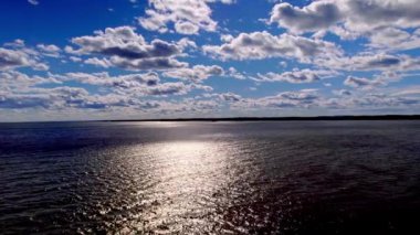 Vanern Gölü 'nün güzel panoramik manzarası yaz mevsiminde Varmland İsveç Havacılık manzarası beyaz kabarık bulutlar ve mavi gökyüzü ile bir göl üzerindedir. İnsansız hava aracı ileri uçar ve bir gölün üzerinden uçar, gökyüzü, bulutlar ve arka planda dağlarla birlikte..