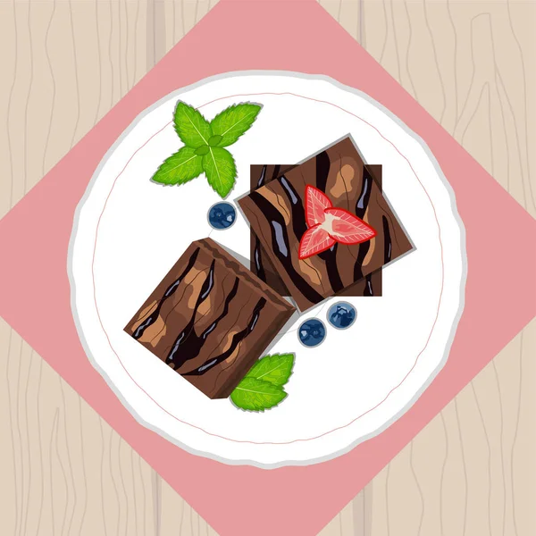 Brownies cake pieces with strawberries, blueberries and mint on ceramic plate top view