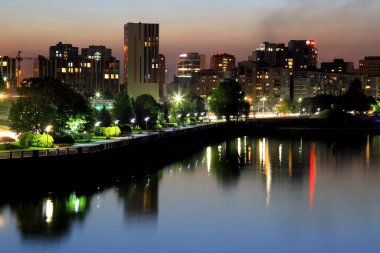 Güzel modern binalar, gökdelenler ve gece kuleleri manzaralı büyük şehir akşam Dinyeper Nehri 'ne yansıyor. Dnipro, Dnepropetrovsk, Ukrayna