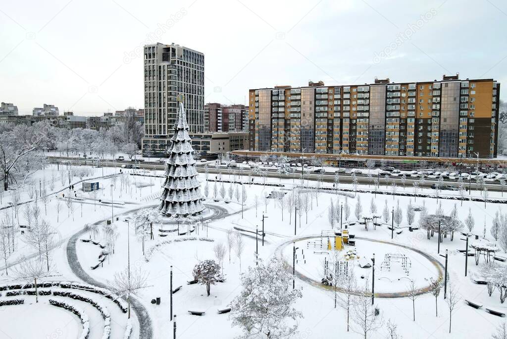 Winter city snow landscape, background, Christmas tree. Winter street park, tall buildings, skyscrapers. Aerial view from drone. Ukraine, Dnipro city Dnepropetrovsk