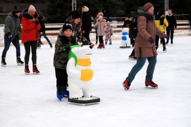 Outdoor winter ice rink. Children and adults learn to skate. Active family sport. School sports, entertainment for children on winter holidays, Christmas, New Year Dnipro, Ukraine, 2021-12-19