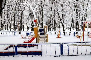 Winter park square with a children s playground, covered with snow. Children's slides and swings in winter. Dnipro, Dnipropetrovsk, Ukraine