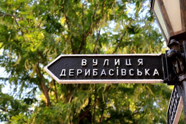 Vintage road sign stands on Deribasovskaya Street in famous city Odessa, Ukraine. Well-known Deribasivska street is popular from Ukrainian and foreign tourists clipart