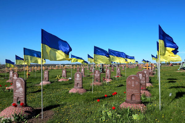 military cemetery where soldiers who died in Russian war against Ukraine are buried. State Ukrainian flag flutter over graves and monuments. Dnipro city, Ukraine, May 7, 2022.