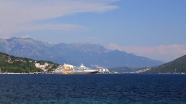 Deniz Burnu, Karadağ 'ın yüksek dağları yakınlarındaki Kotor Körfezi' nde büyük beyaz bir yolcu gemisi duruyor. Turizm, seyahat, eğlence. Okyanusta yolcu gemisi, yaz tatili. Herceg Novi, Karadağ, 2021-06-17