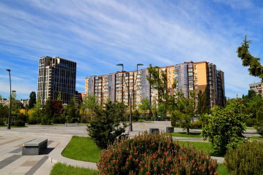 Beautiful park against tall houses, buildings. skyscrapers landscape. Spring, summer street in Ukrainian city Dnipro, Dnepropetrovsk, Ukraine