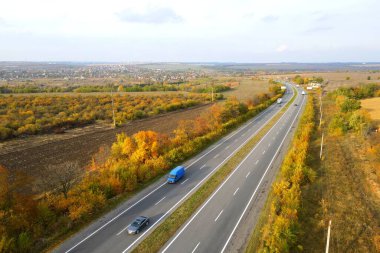 Otoyol, sonbaharda yol yaprakların düşüşü. Arabalar asfalt yolda gider. Drone 'dan peyzaj fotoğrafçılığı. Autumn Highway, Ukrayna