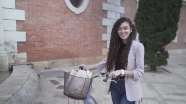 Beautiful Moroccan Lady With Long Curly Hair Posing With A Bicycle Outdoor. zoom-out - Horizontal