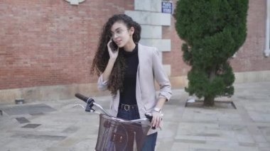 Bisikletli Faslı Kız 'a sokakta telefon var. - Ortalama çekim - Yatay