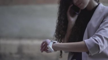 Akıllı telefondan konuşan kız kol saatine bakıyor. Kapat - Yatay