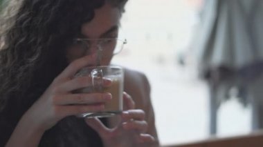 Beautiful Young Moroccan Lady Drinks Coffee While Working On Her Laptop In A Cafe. Closeup - Horizontal