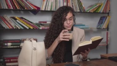 Young Moroccan Woman Drinking Coffee While Reading An Interesting Book. - closeup - Horizontal