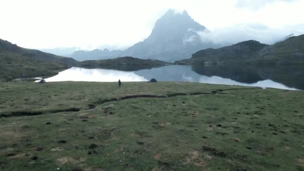 湖の横のテントの空中前方移動ショット日没後の曇りの夜にフランスのピレネー山脈のAyousと美しい山の範囲 水平4Kビデオ — ストック動画