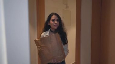 Genç bir bayan, Valencia, İspanya 'da bir apartmanın kapısından girerken kız arkadaşına sarılıp onu karşılar. - Orta boy yakın çekim - Yatay 4K