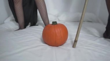 Cadılar Bayramı Cadısı Kostümlü Komik Güzel Kadınlar Yatak odasında cadı süpürgesi ve balkabağıyla oynuyor. Eğik - Yatay 4K