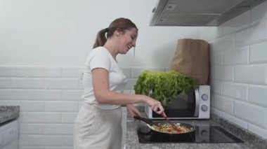 Mutlu Kafkas ev hanımı dans ederken evde yemek pişiriyor. Orta Çekim - Yatay