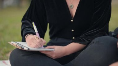Not defterinde bir kalemle el yazısı, görüntüyü kapat. Alt vücut, kadın - Yatay 4K video