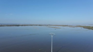 Mavi gökyüzü ve beyaz bulutlar altında İspanya 'nın Albufera doğal parkında suya gömülü sıra sıra ilerleyen tarımsal tarla ve su sulama görüntülerini gösteren güzel bir hava aracı. - 4K Yatay Görüntü