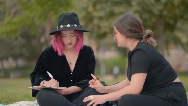 ピンクの髪の少女はメモ帳にメモを取り友人が彼女に指示する間 閉じます 水平4Kビデオ — ストック動画