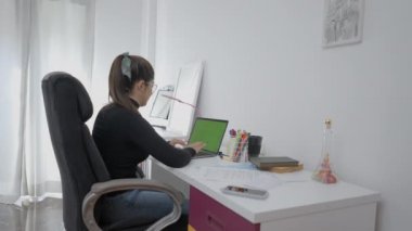 Uzaktan çekilen bir fotoğraf, masada oturan ve bilgisayarında hızla yazan genç bir kız. Kolombiya Üniversitesi 'nde okuyan bir öğrenci. - 4K Yatay Görüntü