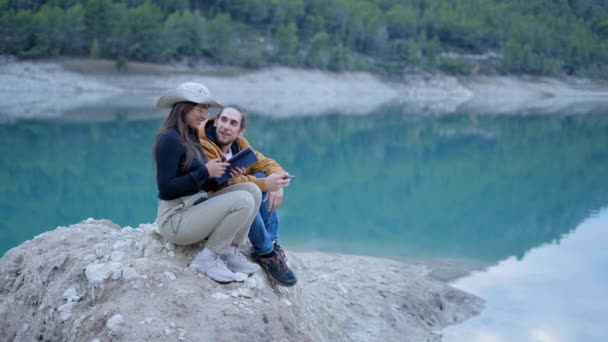 Young Couple Sit Rock Still Lake Talk Kiss Use Tablet — Wideo stockowe