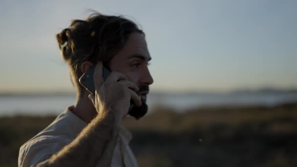 Zbliżenie Twarz Brodatego Mężczyzny Rozmawiającego Przez Telefon Zewnątrz Zachodzie Słońca — Wideo stockowe