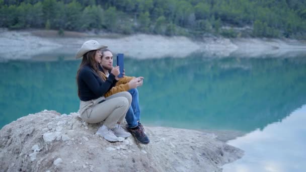Young Couple Sit Rock Lake Take Photos Phone Tablet Horizontal — Video