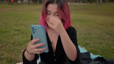 Sensual pink haired european girl taking selfies on smartphone at the park - Horizontal 4K video