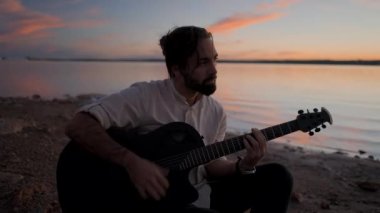 Günbatımında Torrevieja Pembe Gölü 'nde gitar çalan İspanyol sakallı adam, Alicante - Yatay 4K video