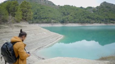 Guadalest, İspanya 'da sırt çantasıyla göl fotoğrafı çeken adamın yan görüntüsü - yatay video