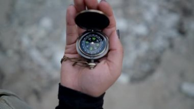 Close view of metal compass spinning in hand of young woman in nature - Horizontal video