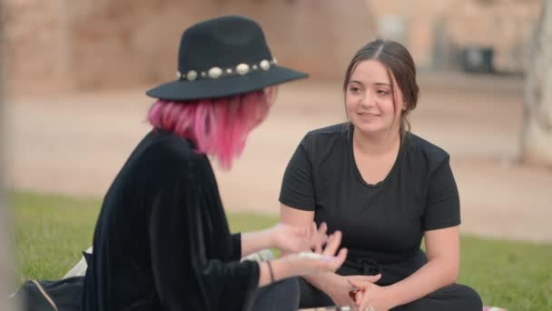 Two Caucasian Young Women Chatting While Sitting Grass Medium Close — Vídeo de stock