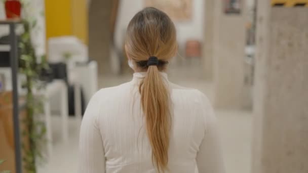 一名戴防护面罩在同事办公室走廊行走的女雇员的后背 跟随镜头 慢动作 水平4K视频 — 图库视频影像