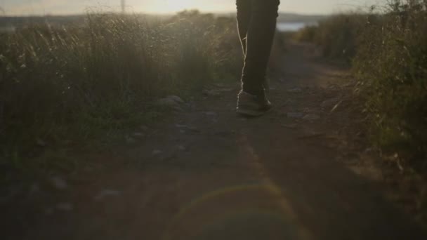 日没時にギターを手に田舎道を歩く男の足撮影後のスローモーション水平4Kビデオ — ストック動画