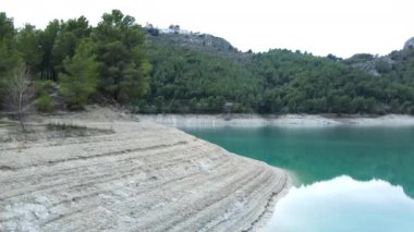 Still lake, forest and eroded stony shore in Guadalest, forward aerial - Horizontal video