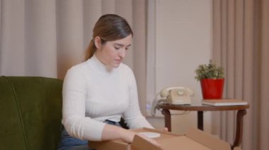 Mutlu kadın karton kutuyu açar ve basit dizaynlı beyaz mücevher kutusunu çıkarır - yatay 4K video
