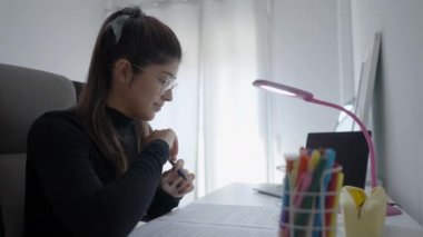 Focused young Colombian woman college university student doing homework assignment using laptop computer typing studying e learning on pc technology sit at home desk,distance online education concept