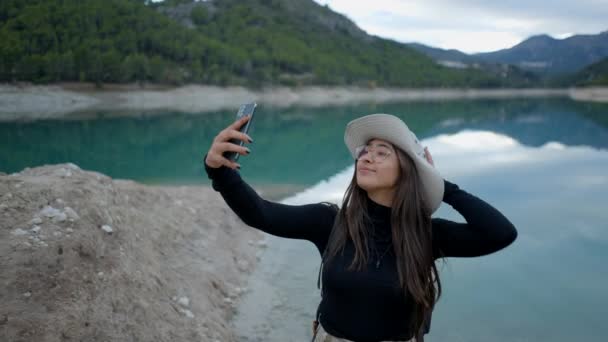 Young Happy Woman Hat Glasses Takes Selfies Phone Lake Horizontal — ストック動画