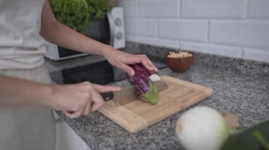 Woman Slicing Eggplant Into Circle On Chopping Board In The Kitchen. - close up - Horizontal