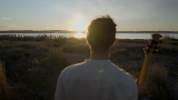 Silhouette Joven Saltando Con Guitarra Atardecer Junto Lago Horizontal Video — Vídeo de stock