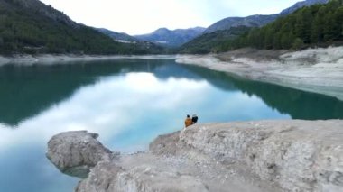 Guadalest 'te göl kenarındaki taşların üzerinde oturan çift tersten yükselen görüntüsü