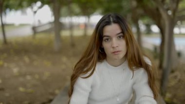 Parktaki genç siyah saçlı kadın kameraya bakar ve dikkatle dinler - 4K Yatay Video