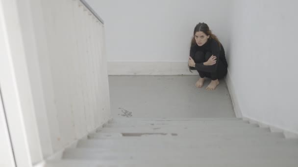 Young Woman Sits Corner Stairwell Looking Scared Slow Pan Horizontal — Vídeo de Stock