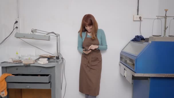 Young Jeweler Wearing Brown Apron Her Shop Using Mobile Phone — Stock Video