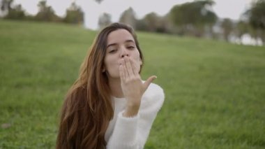 Koyu renk saçlı genç bir kadının kameraya öpücük attığı yakın görüntü - 4K Yatay video