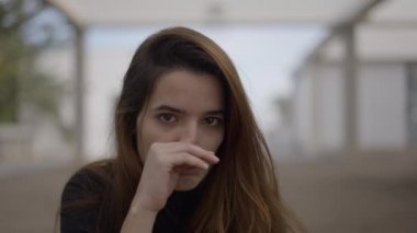 Koyu renk saçlı genç bir kadının açık havada gözyaşlarını silerkenki yakın çekimi - 4K Yatay Video