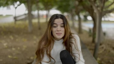 Parktaki genç siyah saçlı kadın kameraya gülümsüyor, slomo - 4K Yatay Video