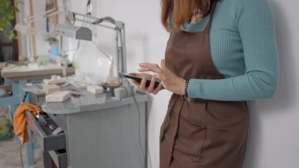 Crop View Young Artisan Browsing Her Smartphone Her Working Place — Vídeos de Stock